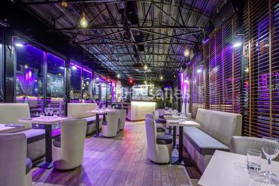 Bar moderne avec comptoir éclairé, bouteilles en arrière-plan, trois verres et une bouteille de champagne au premier plan.