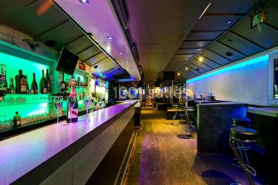 Bar moderne avec comptoir éclairé, bouteilles en arrière-plan, trois verres et une bouteille de champagne au premier plan.