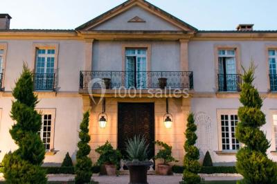 Vue d'une terrasse avec parasols et piscine, encadrée par des haies sombres et un ciel dégagé en arrière-plan.