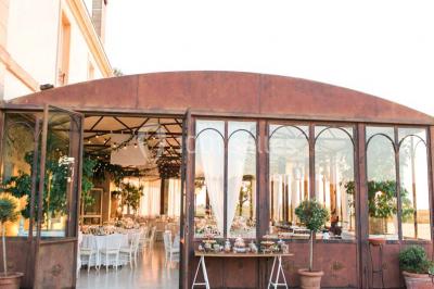 Vue d'une terrasse avec parasols et piscine, encadrée par des haies sombres et un ciel dégagé en arrière-plan.