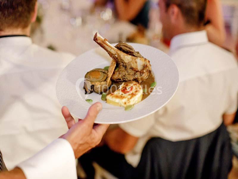 Assiette de viande avec os, accompagnée de légumes et d'une portion de fromage grillé, servie lors d'un repas.