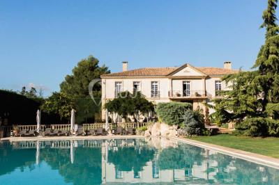 Vue d'une terrasse avec parasols et piscine, encadrée par des haies sombres et un ciel dégagé en arrière-plan.