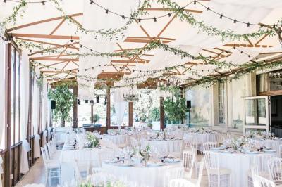 Vue d'une terrasse avec parasols et piscine, encadrée par des haies sombres et un ciel dégagé en arrière-plan.