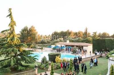 Vue d'une terrasse avec parasols et piscine, encadrée par des haies sombres et un ciel dégagé en arrière-plan.