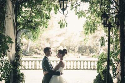 Vue d'une terrasse avec parasols et piscine, encadrée par des haies sombres et un ciel dégagé en arrière-plan.
