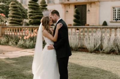 Vue d'une terrasse avec parasols et piscine, encadrée par des haies sombres et un ciel dégagé en arrière-plan.