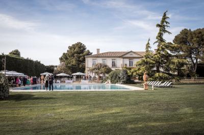 Vue d'une terrasse avec parasols et piscine, encadrée par des haies sombres et un ciel dégagé en arrière-plan.