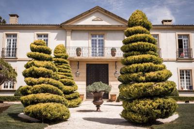 Vue d'une terrasse avec parasols et piscine, encadrée par des haies sombres et un ciel dégagé en arrière-plan.