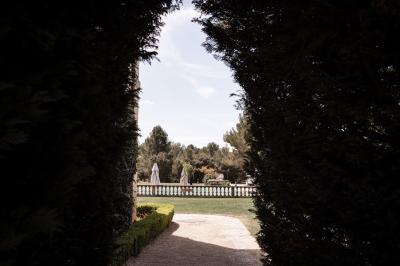 Vue d'une terrasse avec parasols et piscine, encadrée par des haies sombres et un ciel dégagé en arrière-plan.
