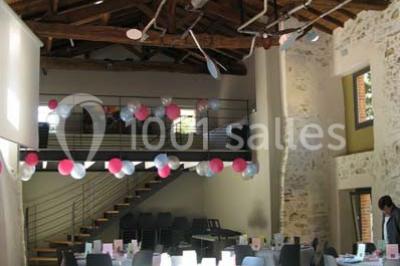 Petit ruisseau bordé de végétation avec des tentes blanches installées pour un événement en arrière-plan.