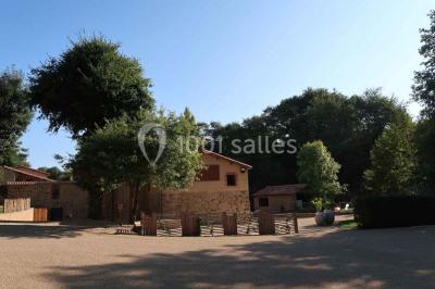 Petit ruisseau bordé de végétation avec des tentes blanches installées pour un événement en arrière-plan.