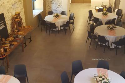 Petit ruisseau bordé de végétation avec des tentes blanches installées pour un événement en arrière-plan.