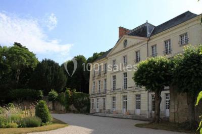 Écran de projection blanc déroulé dans une salle de conférence avec murs en bois et plafond équipé d'un projecteur.