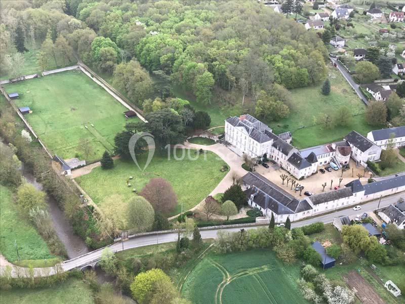 Vue aérienne d'un domaine avec un grand bâtiment principal, des dépendances, des jardins et des espaces verts entourés de…