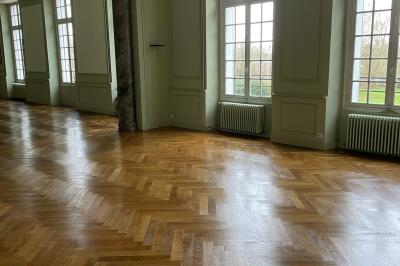 Écran de projection blanc déroulé dans une salle de conférence avec murs en bois et plafond équipé d'un projecteur.
