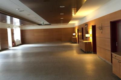 Écran de projection blanc déroulé dans une salle de conférence avec murs en bois et plafond équipé d'un projecteur.