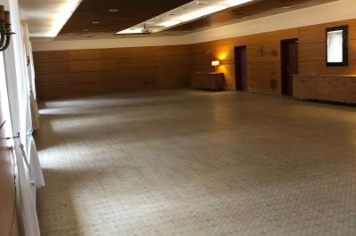 Écran de projection blanc déroulé dans une salle de conférence avec murs en bois et plafond équipé d'un projecteur.