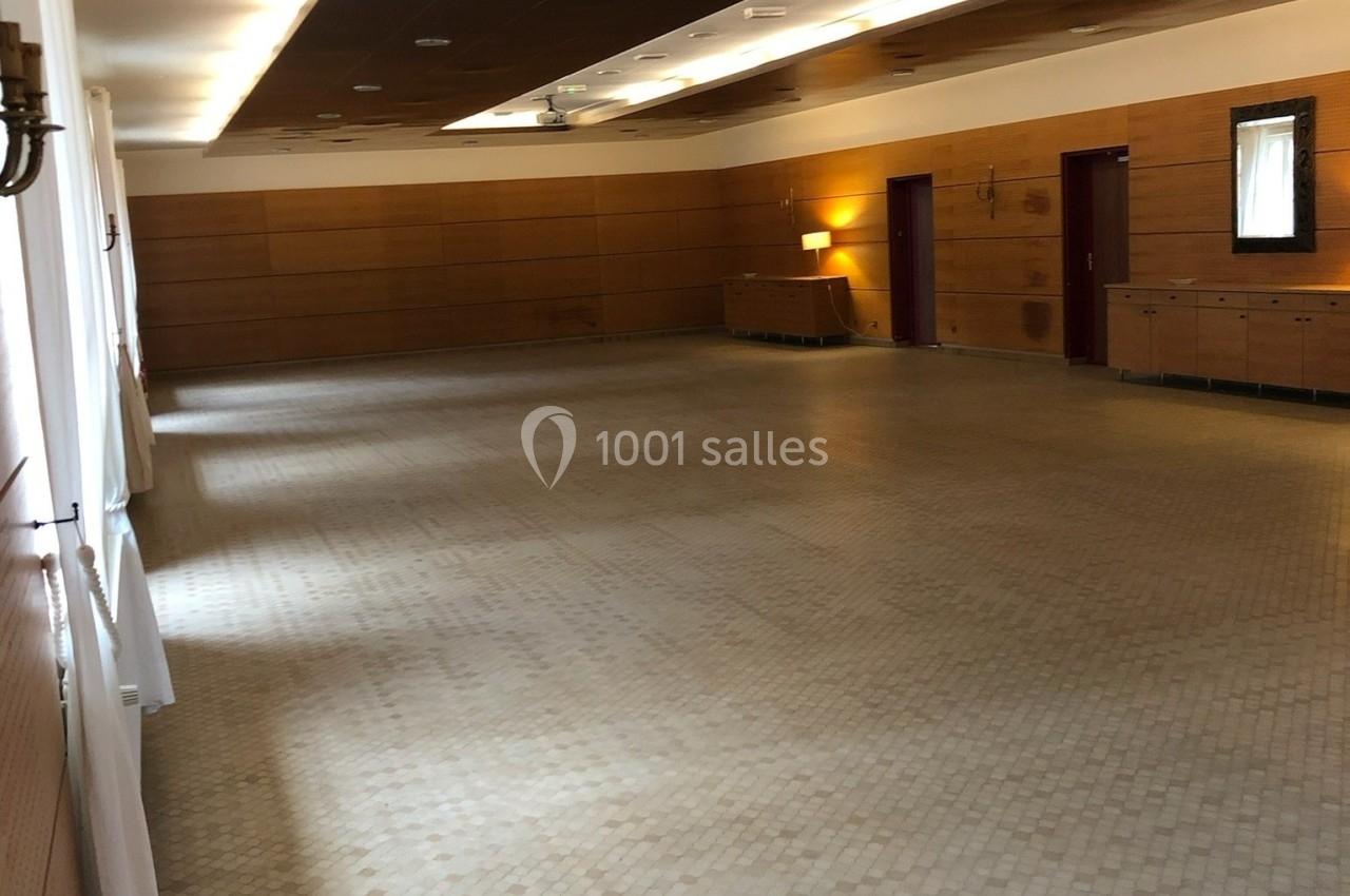 Salle vide avec sol en carrelage clair, murs en bois, éclairage tamisé et mobilier minimaliste.