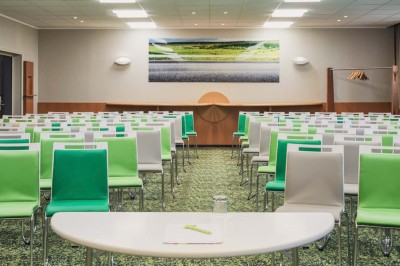 Chambre d'hôtel lumineuse avec lit double, canapé-lit, table basse, fenêtre et décoration moderne.