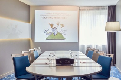 Chambre d'hôtel lumineuse avec lit double, canapé-lit, table basse, fenêtre et décoration moderne.