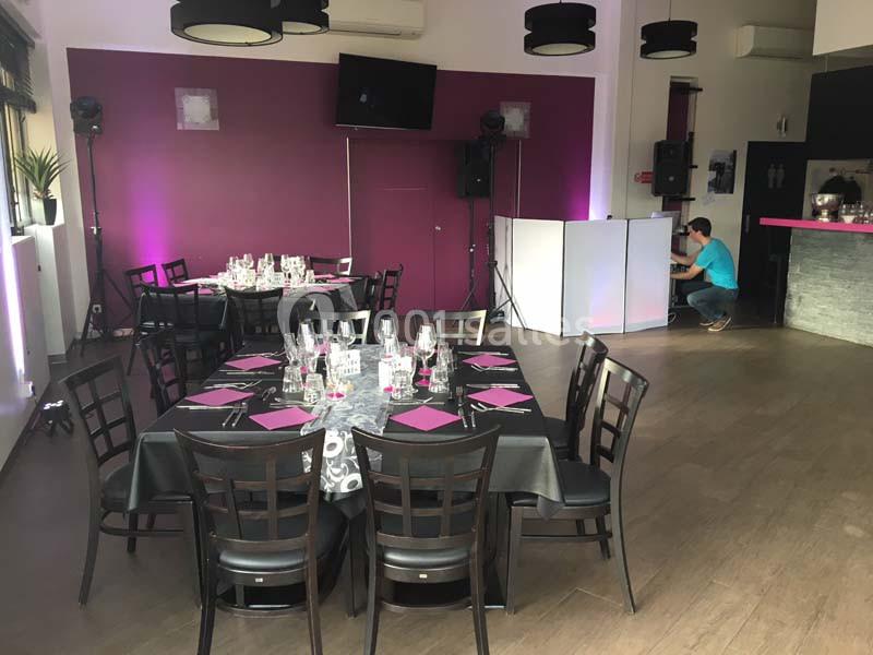 Salle de réception avec tables dressées, nappes noires et serviettes violettes, éclairage tamisé et équipement audio visible.