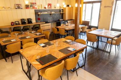 Petit-déjeuner avec croissant, jus d'orange et café sur un plateau, posé sur une table en bois près d'un vase de fleurs.