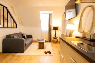 Petit-déjeuner avec croissant, jus d'orange et café sur un plateau, posé sur une table en bois près d'un vase de fleurs.