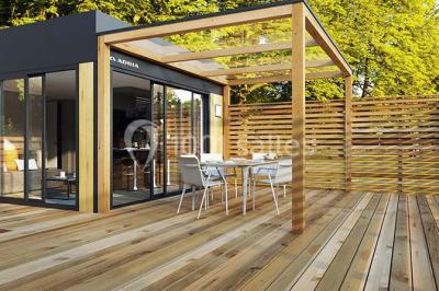Terrasse en bois avec pergola, mobilier de jardin et façade vitrée donnant sur un espace intérieur moderne.