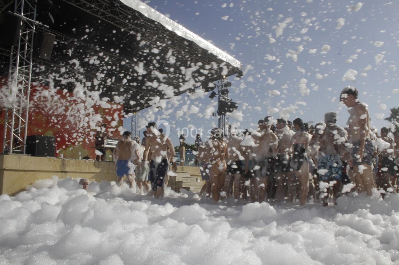 Groupe de personnes participant à une fête en plein air avec de la mousse recouvrant le sol.