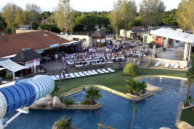 Terrasse en bois avec pergola, mobilier de jardin et façade vitrée donnant sur un espace intérieur moderne.