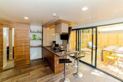 Terrasse en bois avec pergola, mobilier de jardin et façade vitrée donnant sur un espace intérieur moderne.