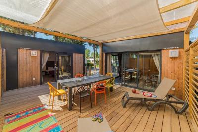 Terrasse en bois avec pergola, mobilier de jardin et façade vitrée donnant sur un espace intérieur moderne.