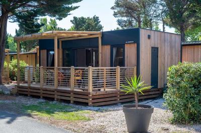 Terrasse en bois avec pergola, mobilier de jardin et façade vitrée donnant sur un espace intérieur moderne.