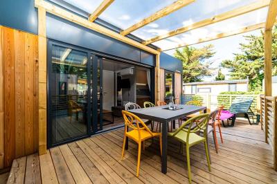 Terrasse en bois avec pergola, mobilier de jardin et façade vitrée donnant sur un espace intérieur moderne.