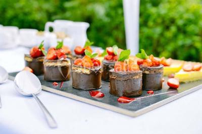 Groupe de personnes assises à des tables en extérieur, assistant à un spectacle sur une scène éclairée en soirée.