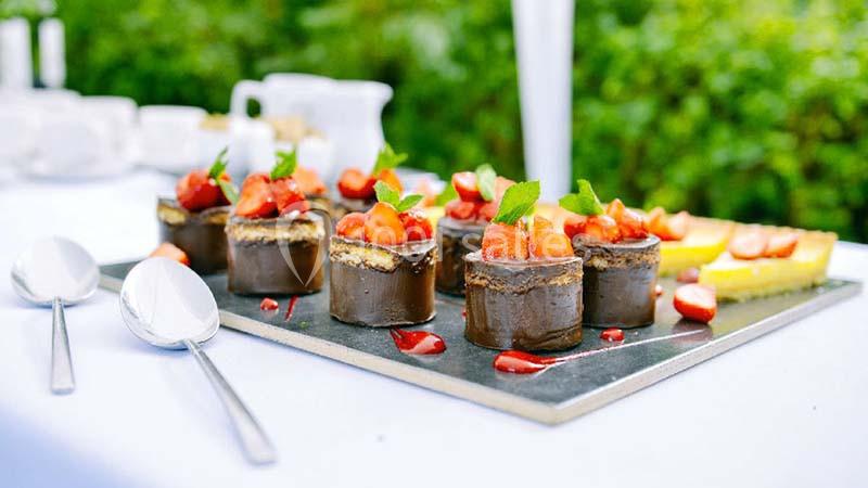 Desserts au chocolat garnis de fraises fraîches et de menthe, présentés sur un plateau lors d'un repas en extérieur.