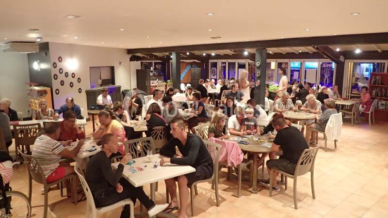 Des personnes assises à des tables dans une grande salle, participant à une activité collective ou un jeu.