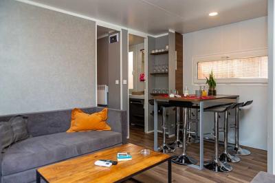 Groupe de personnes assises à des tables en extérieur, assistant à un spectacle sur une scène éclairée en soirée.