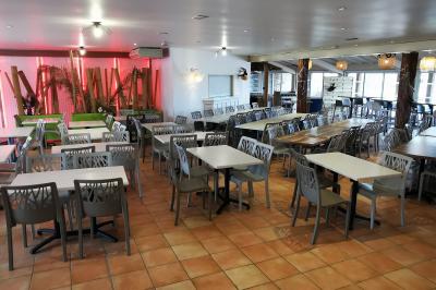 Groupe de personnes assises à des tables en extérieur, assistant à un spectacle sur une scène éclairée en soirée.