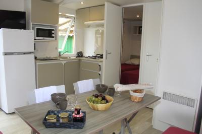 Groupe de personnes assises à des tables en extérieur, assistant à un spectacle sur une scène éclairée en soirée.