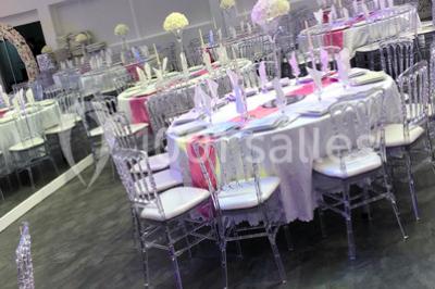 Cuillères transparentes disposées en cercle sur une assiette noire, remplies de semoule garnie de légumes et herbes.