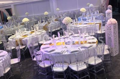 Cuillères transparentes disposées en cercle sur une assiette noire, remplies de semoule garnie de légumes et herbes.