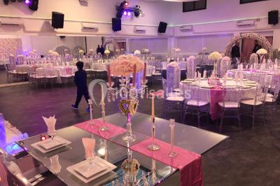 Cuillères transparentes disposées en cercle sur une assiette noire, remplies de semoule garnie de légumes et herbes.