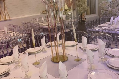 Allée centrale décorée de fleurs blanches et roses, avec arche florale et tables dressées pour un événement festif.