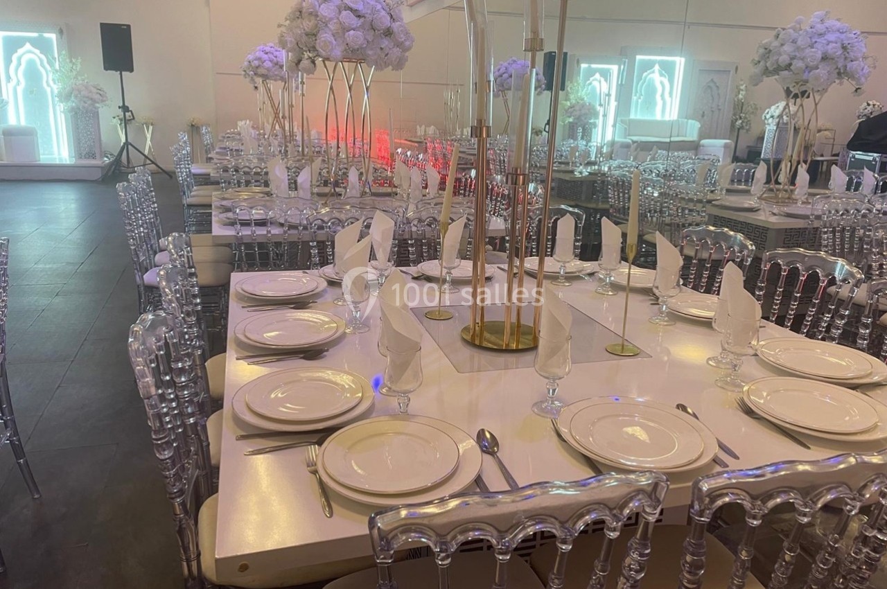 Tables élégamment dressées avec vaisselle blanche, serviettes pliées et chaises transparentes dans une salle de réception…