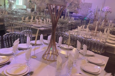 Allée centrale décorée de fleurs blanches et roses, avec arche florale et tables dressées pour un événement festif.
