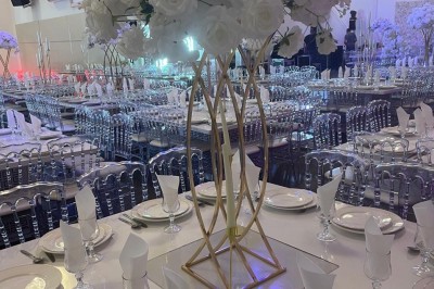 Allée centrale décorée de fleurs blanches et roses, avec arche florale et tables dressées pour un événement festif.