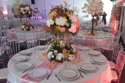 Allée centrale décorée de fleurs blanches et roses, avec arche florale et tables dressées pour un événement festif.