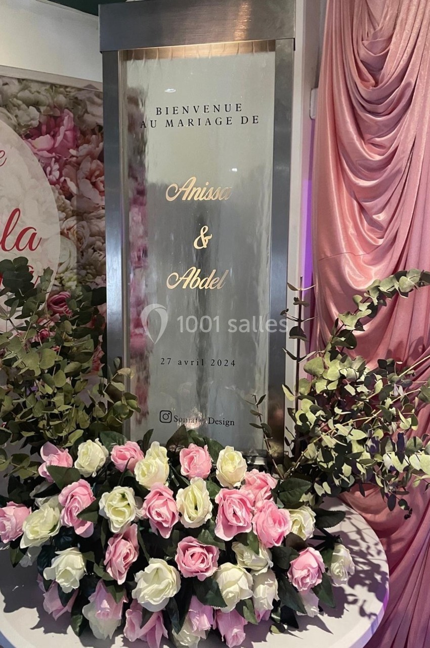 Panneau de bienvenue pour un mariage entouré de roses roses et blanches et de feuillage décoratif.