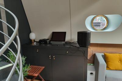 Cuisine étroite avec plaques de cuisson, étagères remplies de cartons et vaisselle, et un réfrigérateur en acier inoxydable.